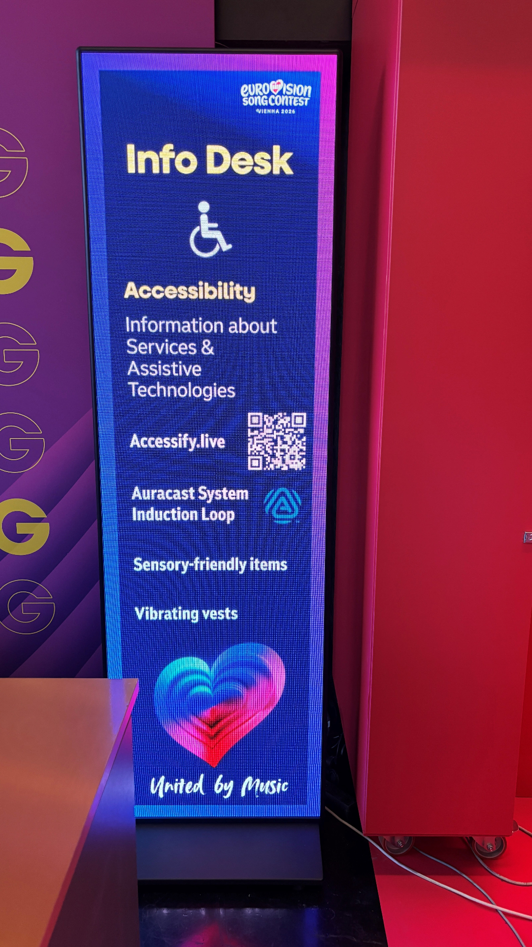Accessify Info Desk display inside the Wiener Stadthalle showing accessibility services, QR code and Auracast information